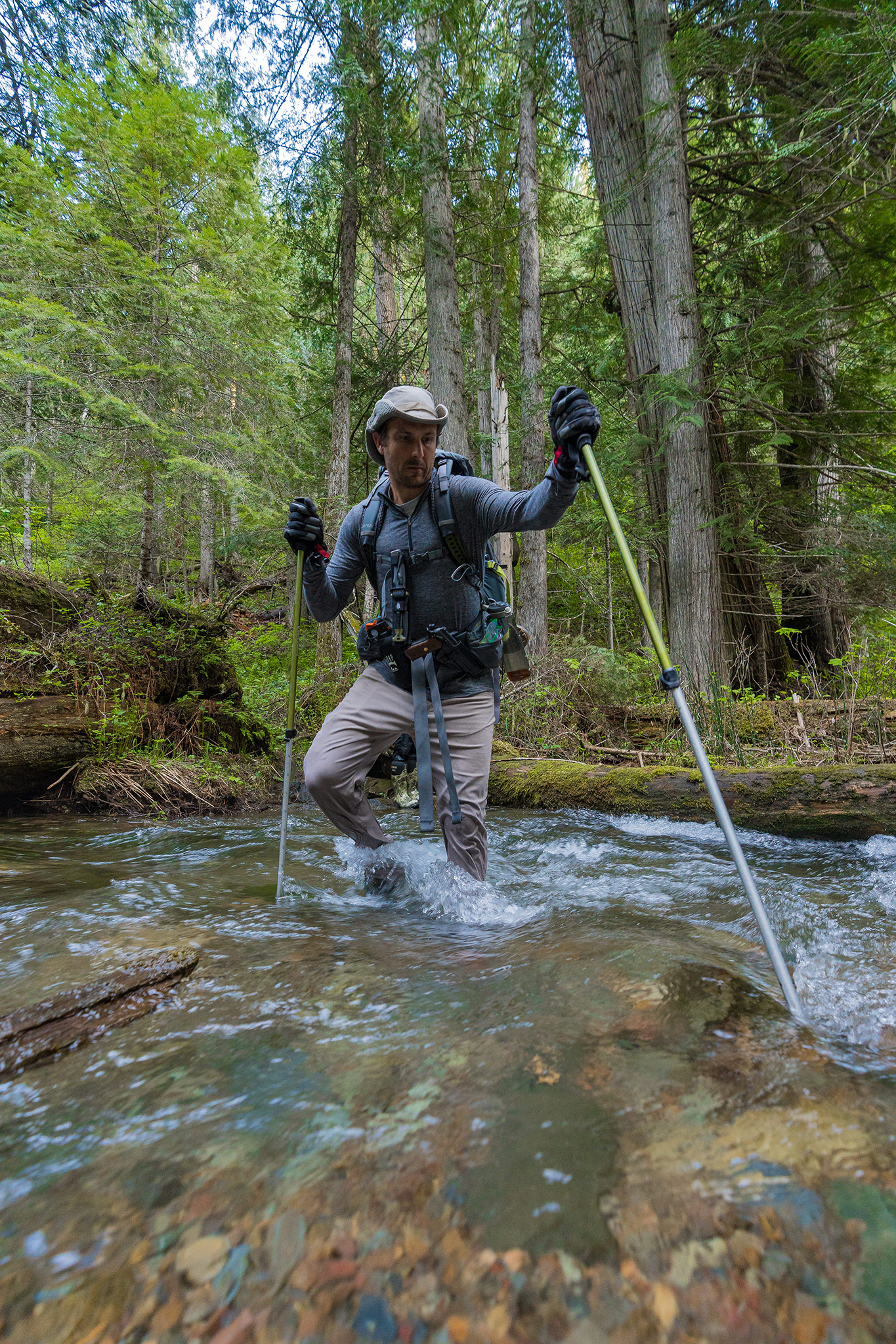 Michael Hollis carefully plants his trekking pole for stability while crossing the creek.
