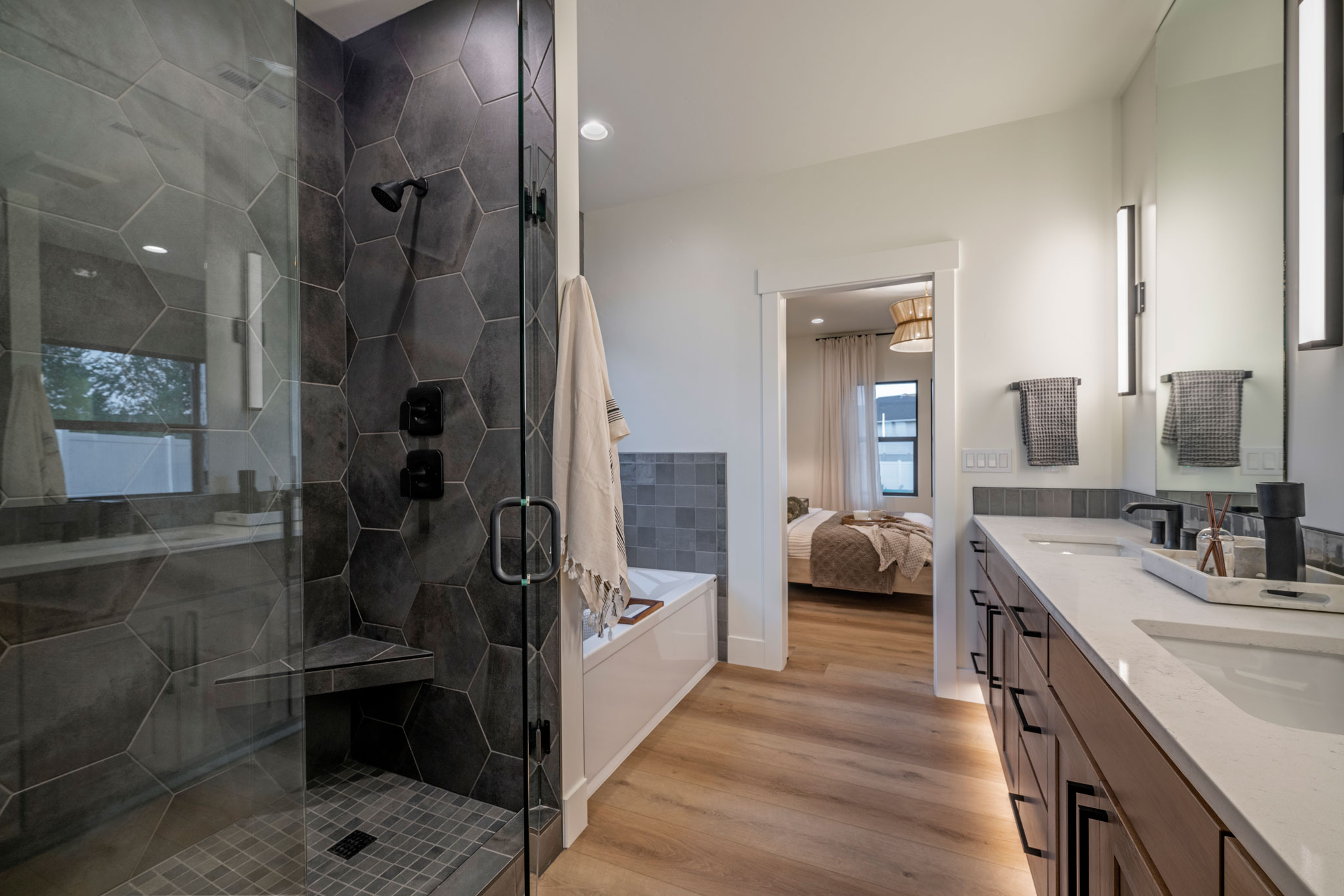 The primary bathroom includes darker stone on the walls of the shower but brighter tones in the rest of the space.